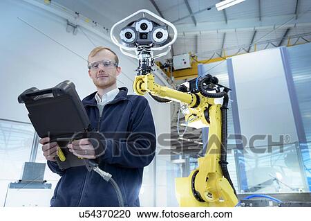Stock Image - Portrait of engineer with robot in robotics research facility. Fotosearch