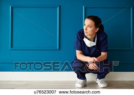 Stock Photo - Portrait of female surgeon, crouching, looking away, pensive expression. Fotosearch