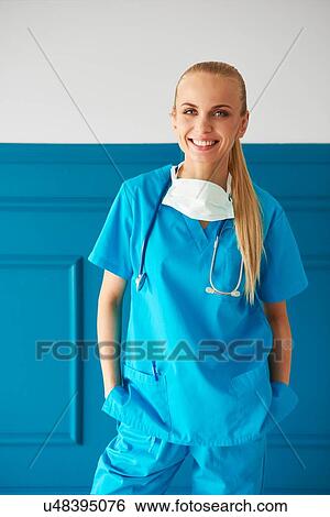 Stock Photograph - Portrait of female surgeon wearing surgical scrubs, smiling. Fotosearch