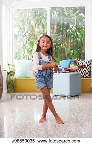 Portrait of girl in living room holding toy camera View Large Photo Image Stock Photography - Portrait of girl in living room holding toy camera. Fotosearch