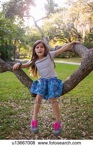Portrait of girl, outdoors, sitting on tree branch View Large Photo Image Stock Photo - Portrait of girl, outdoors, sitting on tree branch. Fotosearch