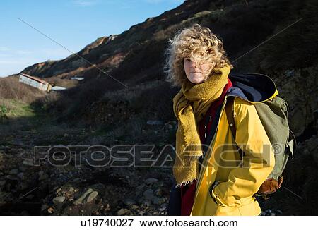 Stock Photo - Portrait of girl with retro backpack hiking near former NATO fuel station on Normandy coast. Fotosearch