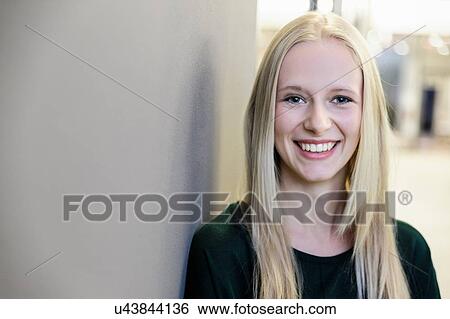 Stock Photograph - Portrait of happy young businesswoman at office entrance. Fotosearch