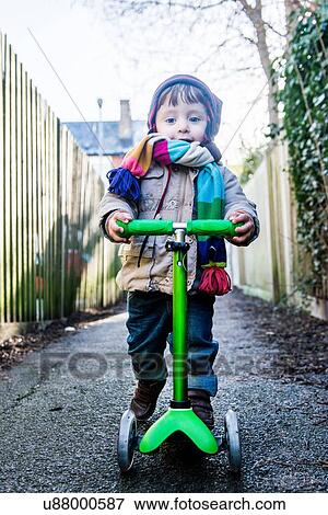 Portrait of male toddler on push scooter in lane View Large Photo Image Stock Photo - Portrait of male toddler on push scooter in lane. Fotosearch