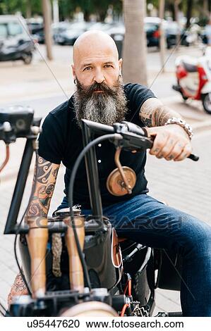 Portrait of mature male hipster astride motorcycle in parking lot View Large Photo Image Stock Image - Portrait of mature male hipster astride motorcycle in parking lot. Fotosearch