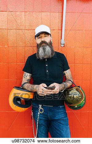 Picture - Portrait of mature male hipster in front of red wall. Fotosearch