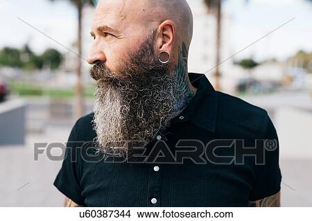 Portrait of mature male hipster with grey beard and earring plug, head and shoulders View Large Photo Image Picture - Portrait of mature male hipster with grey beard and earring plug, head and shoulders. Fotosearch