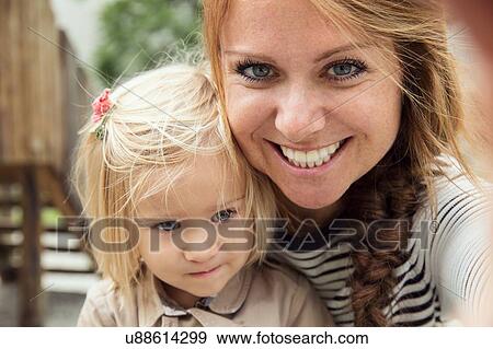 Stock Photo - Portrait of mother and toddler daughter in park, close up. Fotosearch