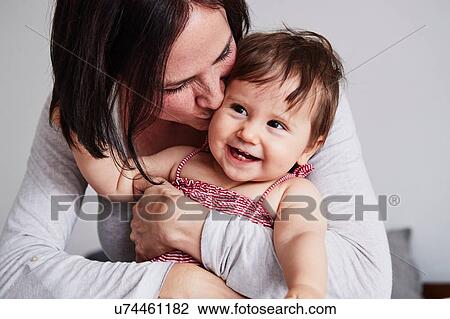 Stock Image - Portrait of mother, hugging baby daughter. Fotosearch