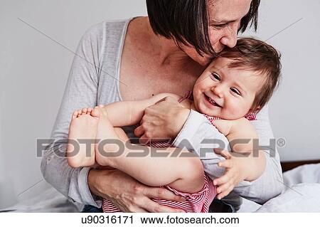 Stock Image - Portrait of mother, hugging baby daughter. Fotosearch