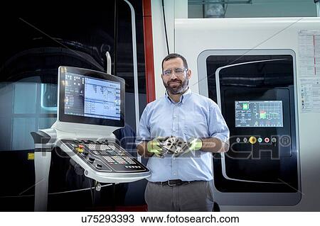 Stock Image - Portrait of operator with stainless steel 3D printer in robotics research facility. Fotosearch