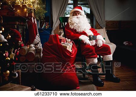 Portrait of Santa Claus, sitting in chair with sack full of presents View Large Photo Image Stock Image - Portrait of Santa Claus, sitting in chair with sack full of presents. Fotosearch
