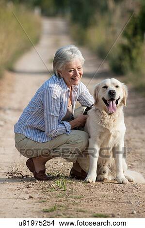 Picture - Portrait of senior woman crouching beside pet dog. Fotosearch