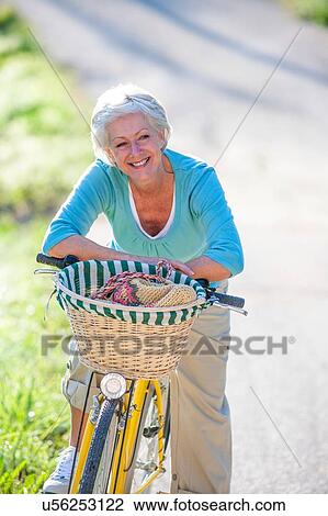 Stock Image - Portrait of senior woman on bicycle. Fotosearch