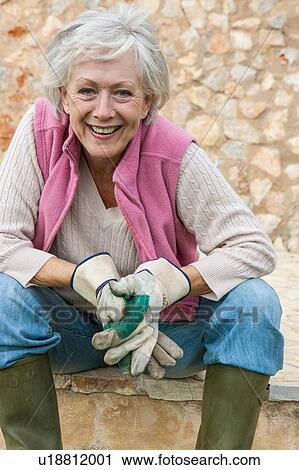 Stock Image - Portrait of senior woman outdoors, wearing gardening gloves. Fotosearch