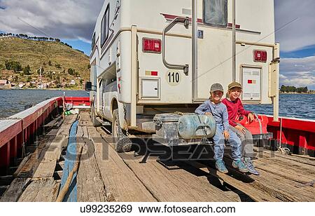 Stock Photo - Portrait of two boys sitting at rear of recreational vehicle, on ferry, Tiquina, La Paz, Bolivia, South America. Fotosearch