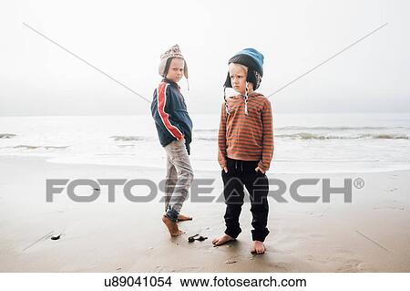 Picture - Portrait of two brothers, standing on beach, wearing knitted hats. Fotosearch
