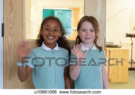 Portrait of two schoolgirls waving in primary school View Large Photo Image Stock Photograph - Portrait of two schoolgirls waving in primary school. Fotosearch