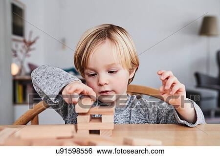 Stock Photograph - Portrait of young boy, building structure with wooden building blocks. Fotosearch