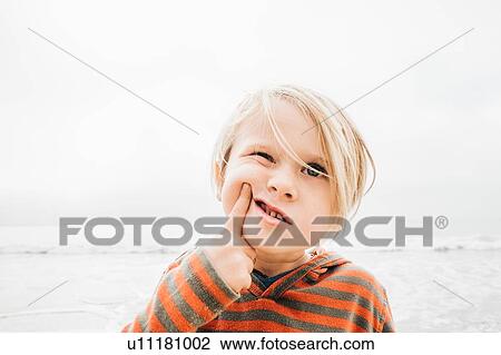 Portrait of young boy on beach, finger on face, making faces View Large Photo Image Stock Image - Portrait of young boy on beach, finger on face, making faces. Fotosearch