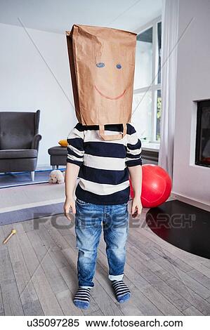 Stock Photography - Portrait of young boy with brown bag on head, drawn face on brown bag. Fotosearch