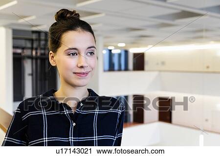 Stock Image - Portrait of young businesswoman in office atrium, head and shoulders. Fotosearch