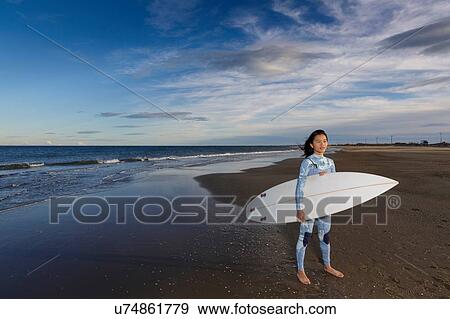 Stock Photo - Portrait of young female surfer standing on beach, Tarragona, Catalonia, Spain. Fotosearch