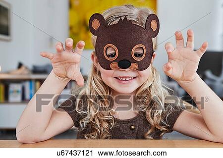 Stock Image - Portrait of young girl wearing bear mask. Fotosearch