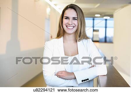 Portrait of young happy businesswoman in office corridor View Large Photo Image Stock Image - Portrait of young happy businesswoman in office corridor. Fotosearch