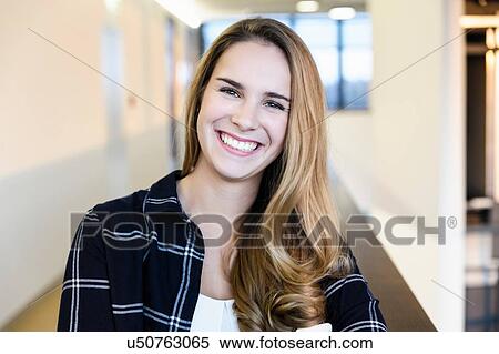 Stock Photography - Portrait of young happy businesswoman in office corridor, head and shoulders. Fotosearch