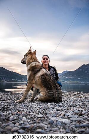 Stock Photograph - Portrait of young woman and dog on riverbank, Vercurago, Lombardy, Italy. Fotosearch