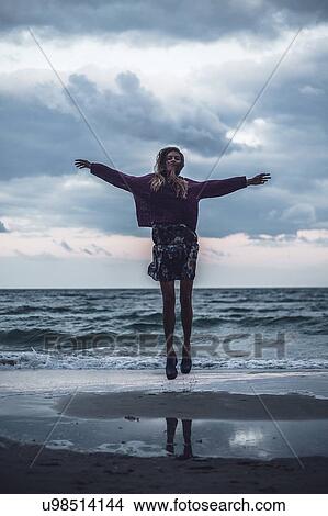 Portrait of young woman jumping on beach at dusk, Odessa Oblast, Ukraine View Large Photo Image Picture - Portrait of young woman jumping on beach at dusk, Odessa Oblast, Ukraine. Fotosearch