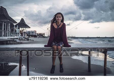 Portrait of young woman sitting on pier at dusk, Odessa Oblast, Ukraine View Large Photo Image Stock Photograph - Portrait of young woman sitting on pier at dusk, Odessa Oblast, Ukraine. Fotosearch