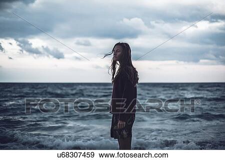 Portrait of young woman standing on beach with eyes closed at dusk, Odessa Oblast, Ukraine View Large Photo Image Stock Photo - Portrait of young woman standing on beach with eyes closed at dusk, Odessa Oblast, Ukraine. Fotosearch