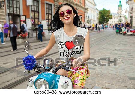 Portrait of young woman wearing pink sunglasses riding scooter on cobbled street, Odessa, Ukraine View Large Photo Image Stock Photo - Portrait of young woman wearing pink sunglasses riding scooter on cobbled street, Odessa, Ukraine. Fotosearch