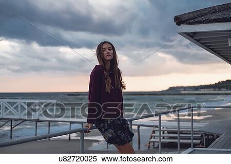 Portrait of young woman with long hair leaning against beach pier at dusk, Odessa Oblast, Ukraine View Large Photo Image Stock Photography - Portrait of young woman with long hair leaning against beach pier at dusk, Odessa Oblast, Ukraine. Fotosearch