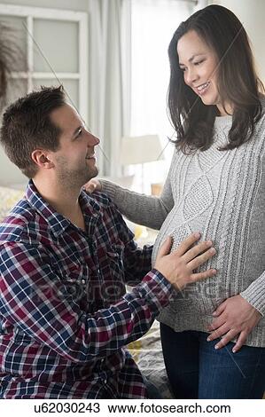 Stock Image - Pregnant woman and partner looking at each other. Fotosearch
