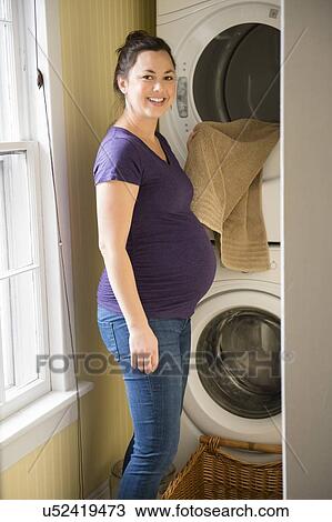 Pregnant woman doing laundry View Large Photo Image Stock Image - Pregnant woman doing laundry. Fotosearch