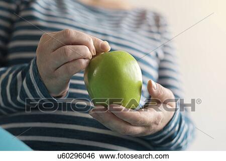 Stock Photograph - Pregnant woman holding green apple.. Fotosearch