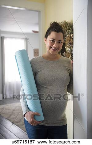 Pregnant woman standing in doorway and holding exercising mat View Large Photo Image Stock Photo - Pregnant woman standing in doorway and holding exercising mat. Fotosearch