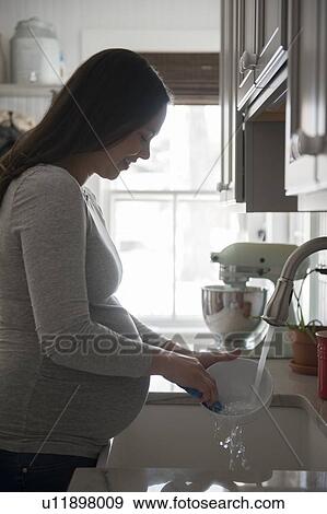 Pregnant woman washing bowl in kitchen sink View Large Photo Image Stock Photo - Pregnant woman washing bowl in kitchen sink. Fotosearch