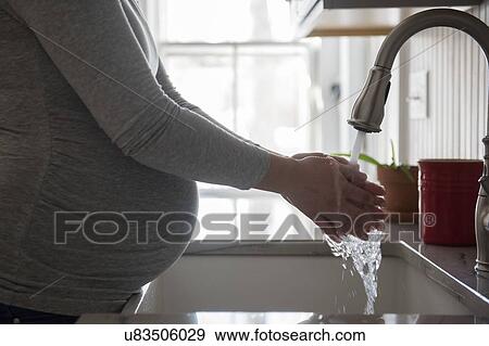 Pregnant woman washing hands in kitchen sink View Large Photo Image Stock Photo - Pregnant woman washing hands in kitchen sink. Fotosearch