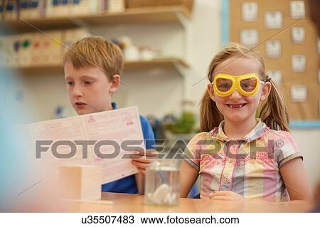 Stock Image - Primary schoolboy and girl doing experiment in classroom. Fotosearch