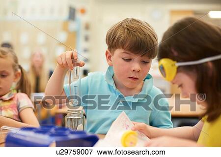 Stock Photo - Primary schoolboy and girls doing test tube experiment in classroom. Fotosearch
