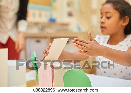 Primary schoolgirl making cardboard structure on classroom desk View Large Photo Image Stock Photograph - Primary schoolgirl making cardboard structure on classroom desk. Fotosearch