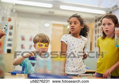 Stock Image - Primary schoolgirls and boys doing experiments in classroom. Fotosearch