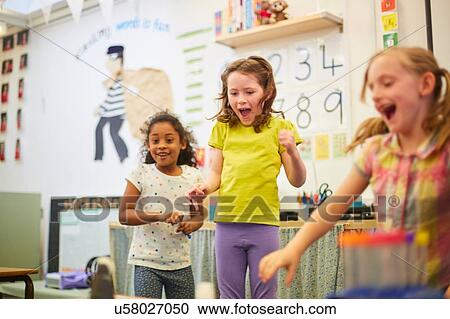 Stock Image - Primary schoolgirls fooling around in classroom. Fotosearch