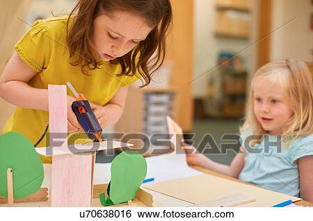 Primary schoolgirls making cardboard model at classroom desk View Large Photo Image Stock Photograph - Primary schoolgirls making cardboard model at classroom desk. Fotosearch