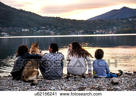Rear view of boy with family and dog by river at dusk, Vercurago, Lombardy, Italy View Large Photo Image Stock Image - Rear view of boy with family and dog by river at dusk, Vercurago, Lombardy, Italy. Fotosearch