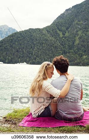 Stock Photo - Rear view of couple sitting by Achensee, Innsbruck, Tirol, Austria, Europe. Fotosearch